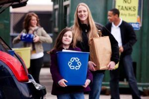 A group of people carrying recycling bins in front of a no tanks sign
