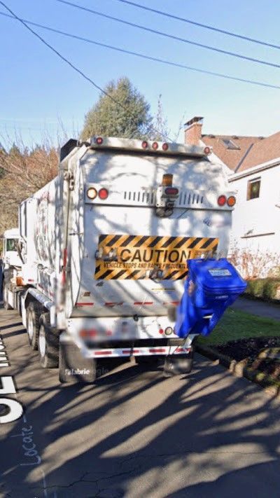 A garbage truck is parked on the side of the road.
