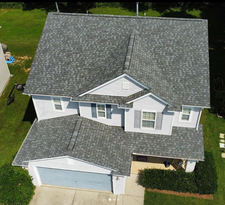 An aerial view of a white house with a gray roof.