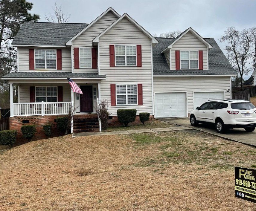 A large white house with red shutters and a car parked in front of it.
