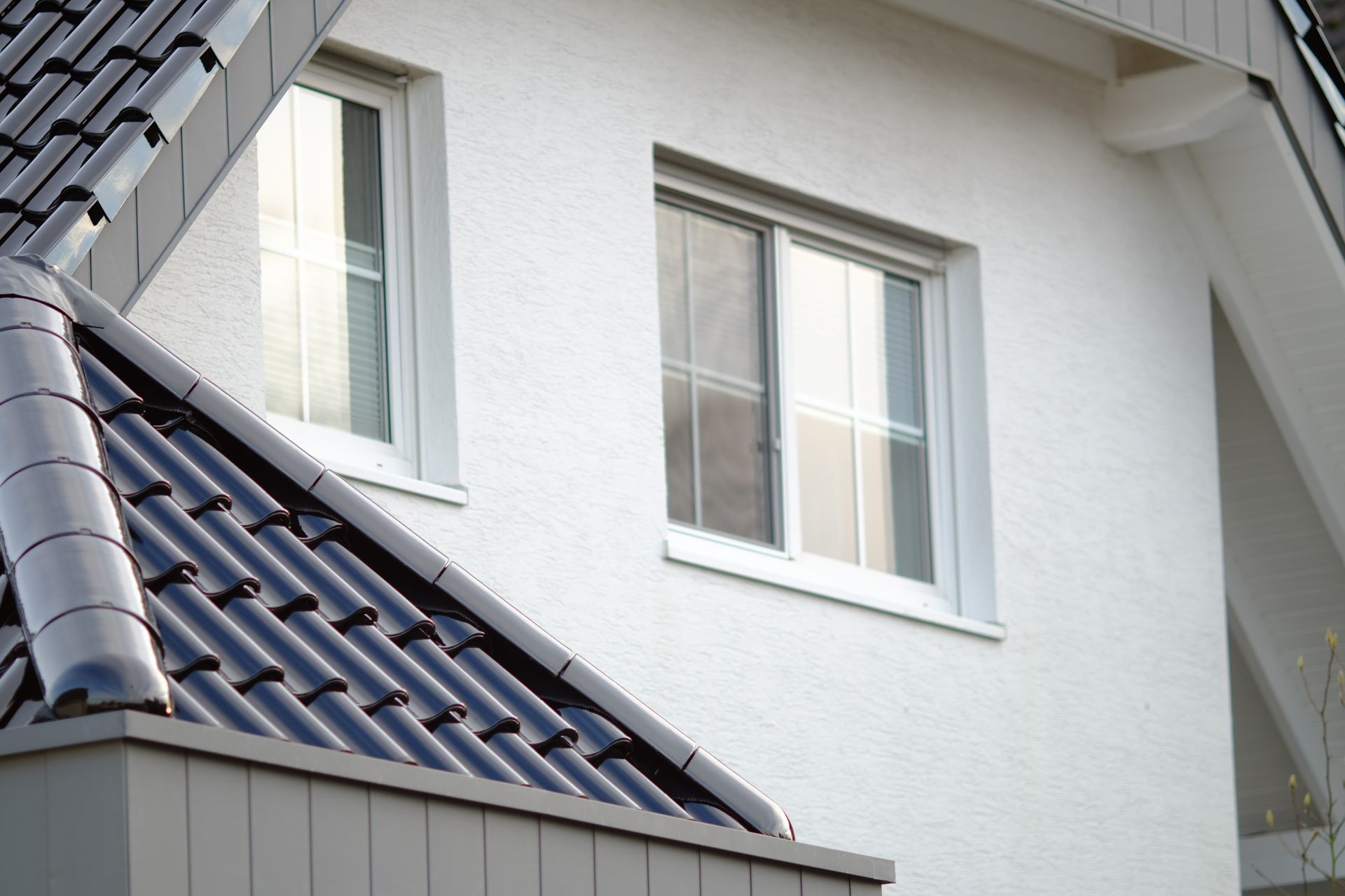 White stucco building with two windows and a dark tiled roof.