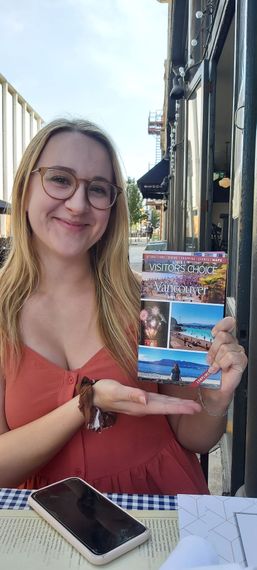 Young woman sitting in a red love seat, reading her Vancouver travel guide