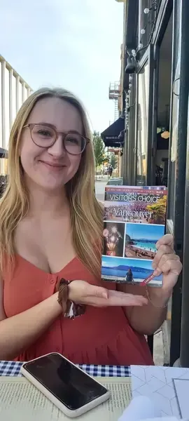 Young woman sitting in a red love seat, reading her Vancouver travel guide