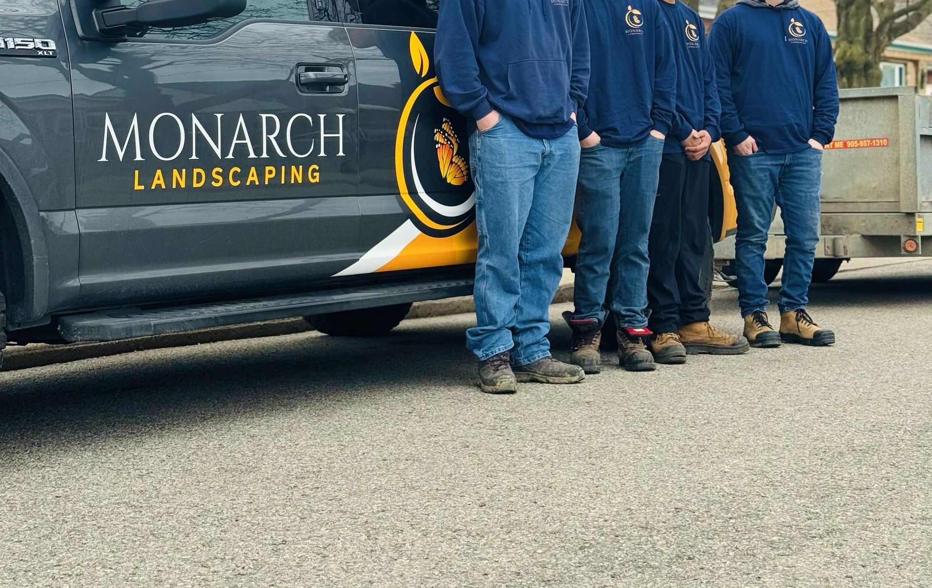 A group of men are standing in front of a monarch landscaping truck.