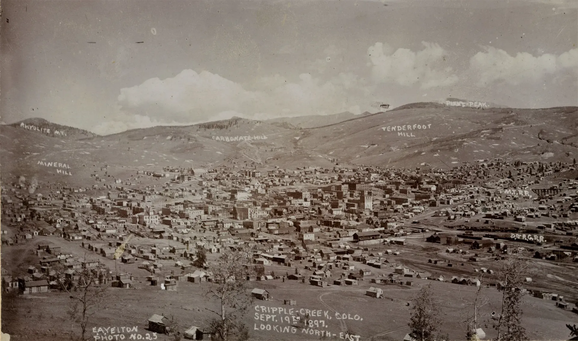 A black and white photo of a city with mountains in the background