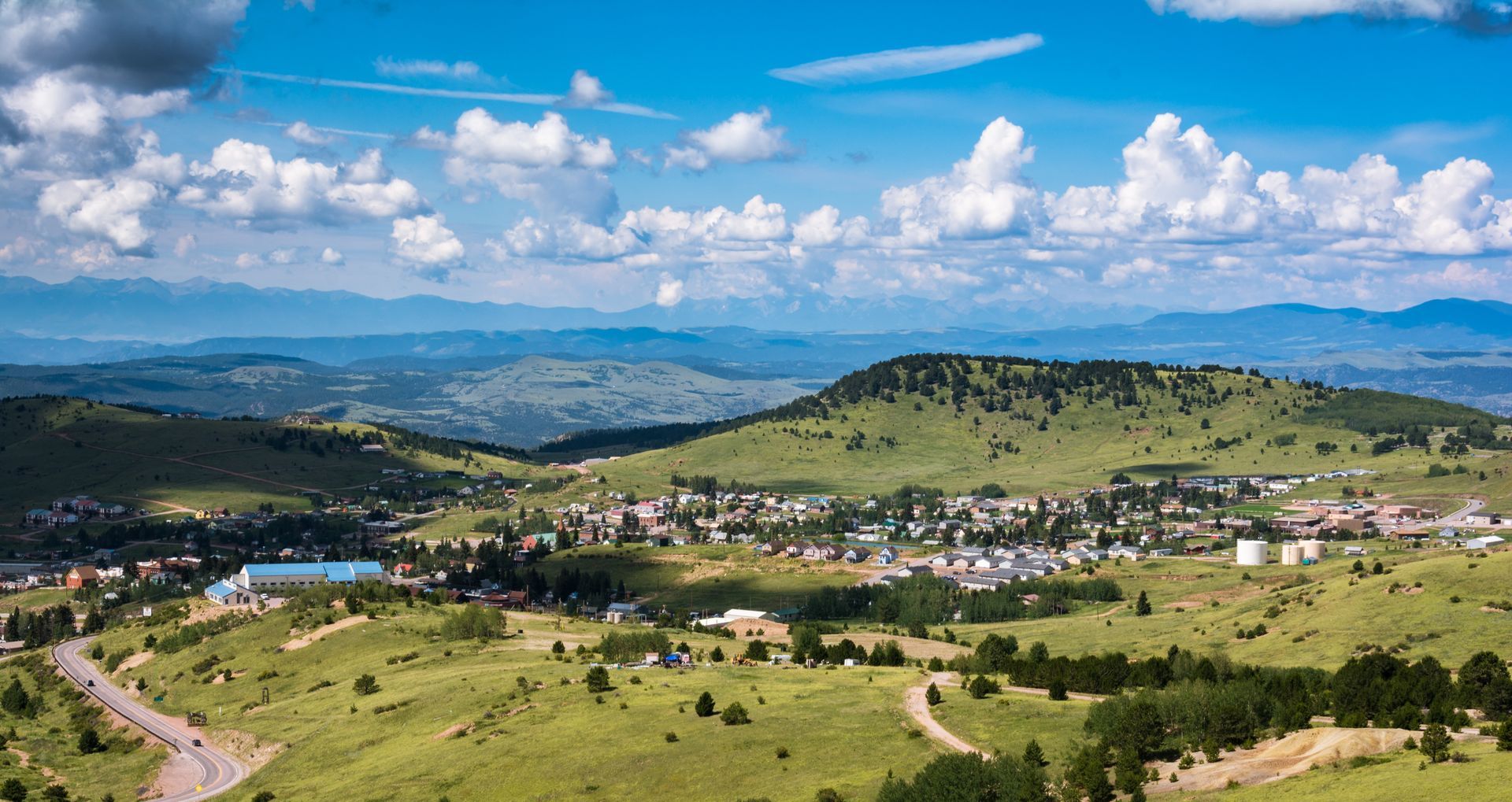 An aerial view of a small town surrounded by mountains on a sunny day.
