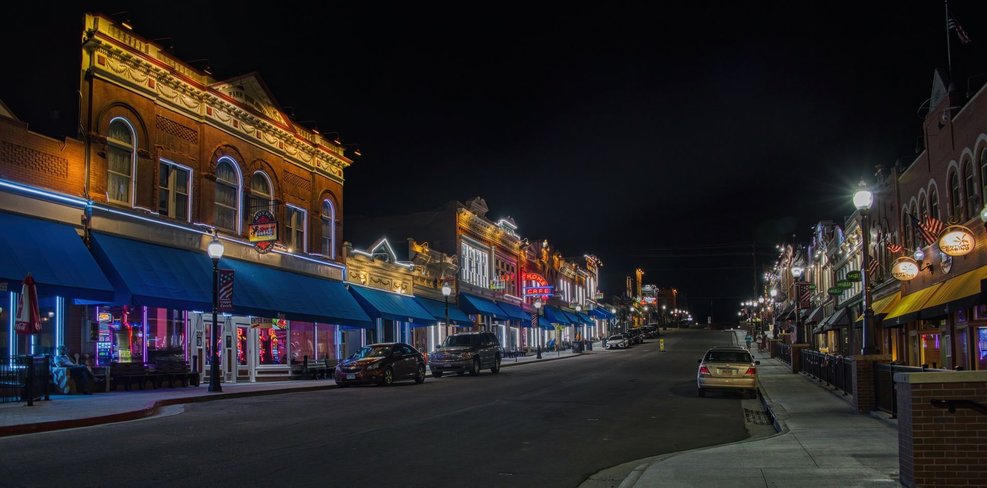 A row of buildings are lit up at night in a small town.