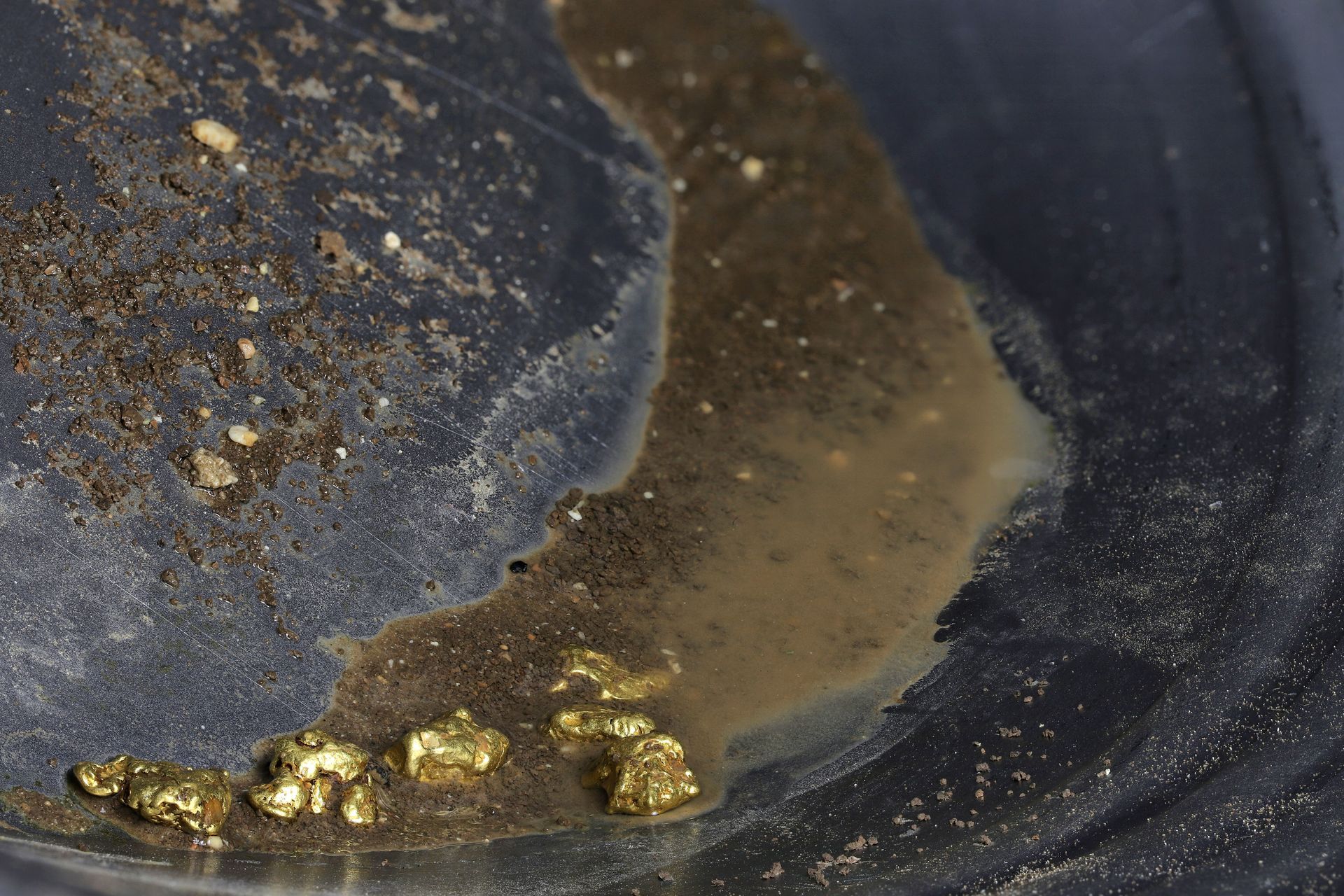 A close up of gold nuggets on a black surface