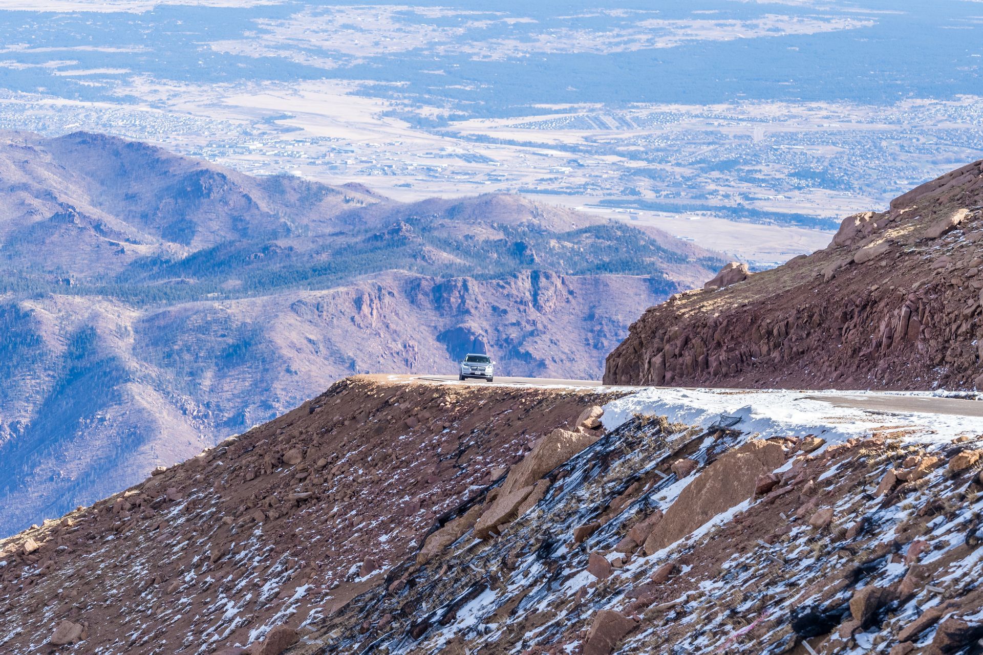 A car is driving down a snowy mountain road.