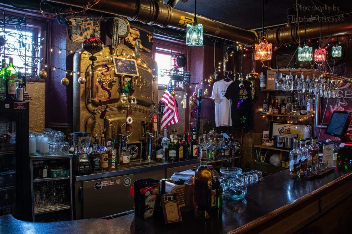 A bar with a lot of bottles and glasses on it.