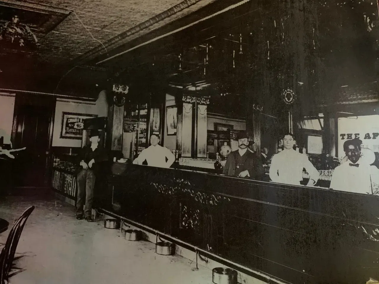 A black and white photo of people standing at a bar