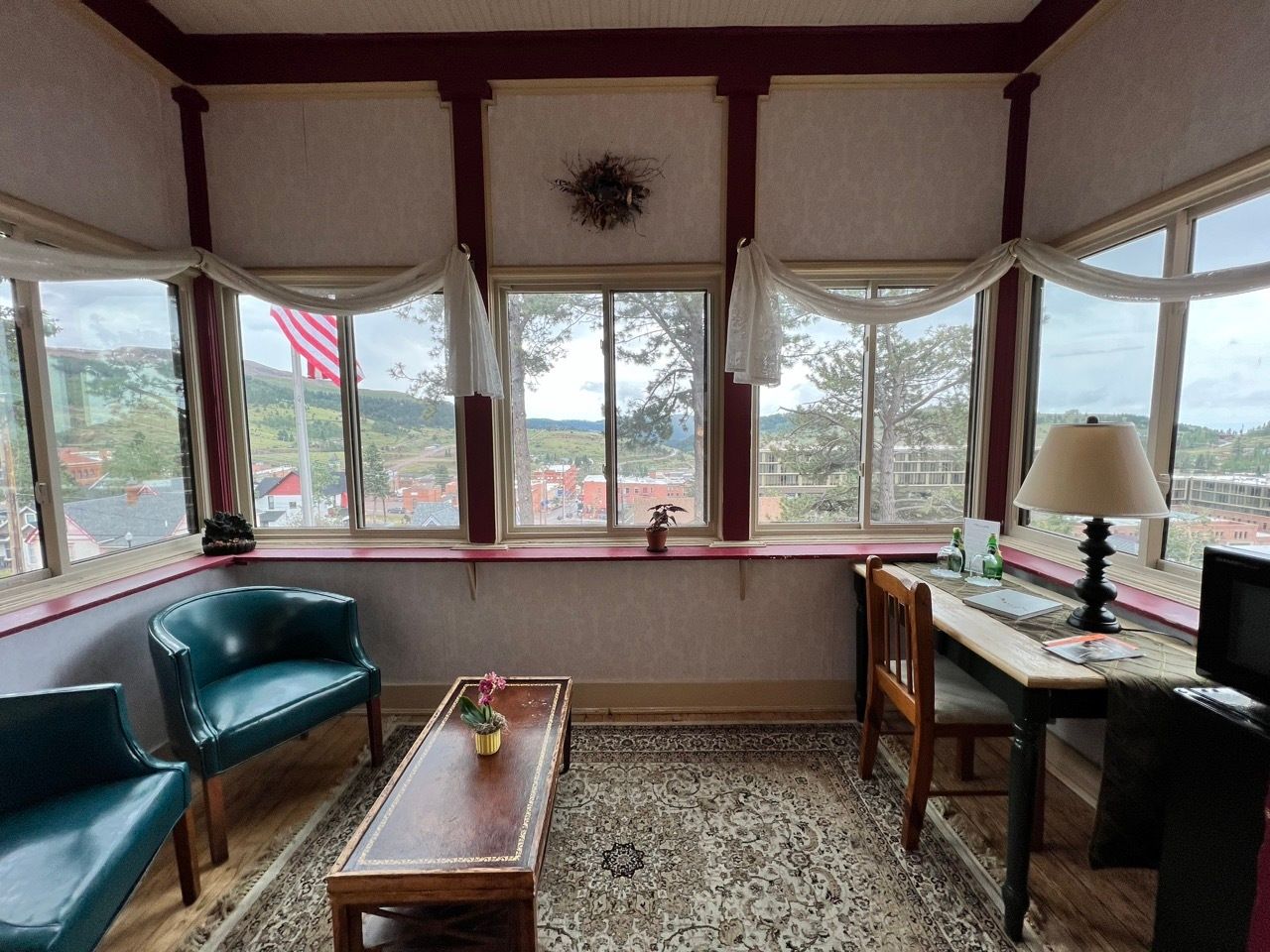 A living room with a lot of windows and a desk