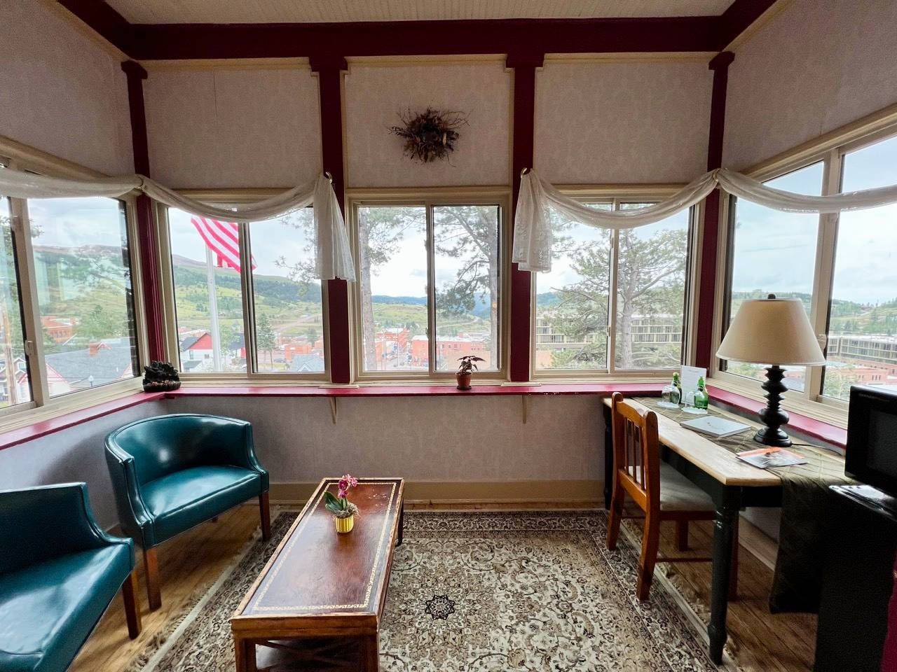 A living room with a lot of windows and a desk