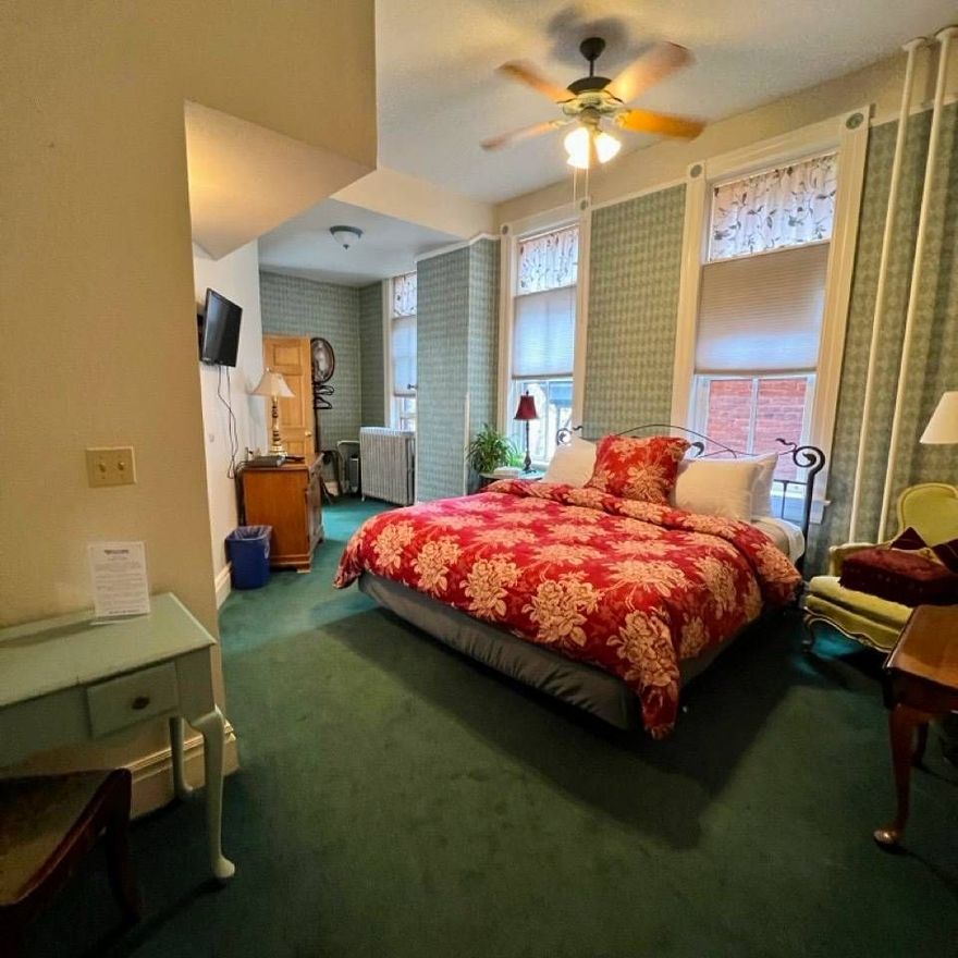 A hotel room with a large bed and a ceiling fan