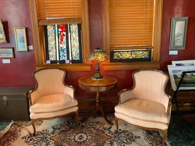Two chairs are sitting next to each other in a room with a table and a lamp.