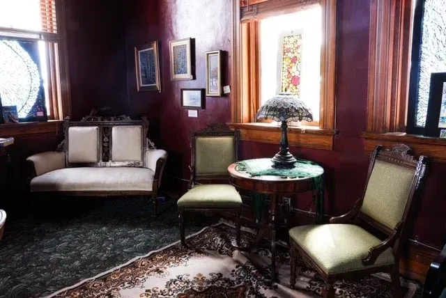 A living room with a couch , chairs , a table and a lamp.
