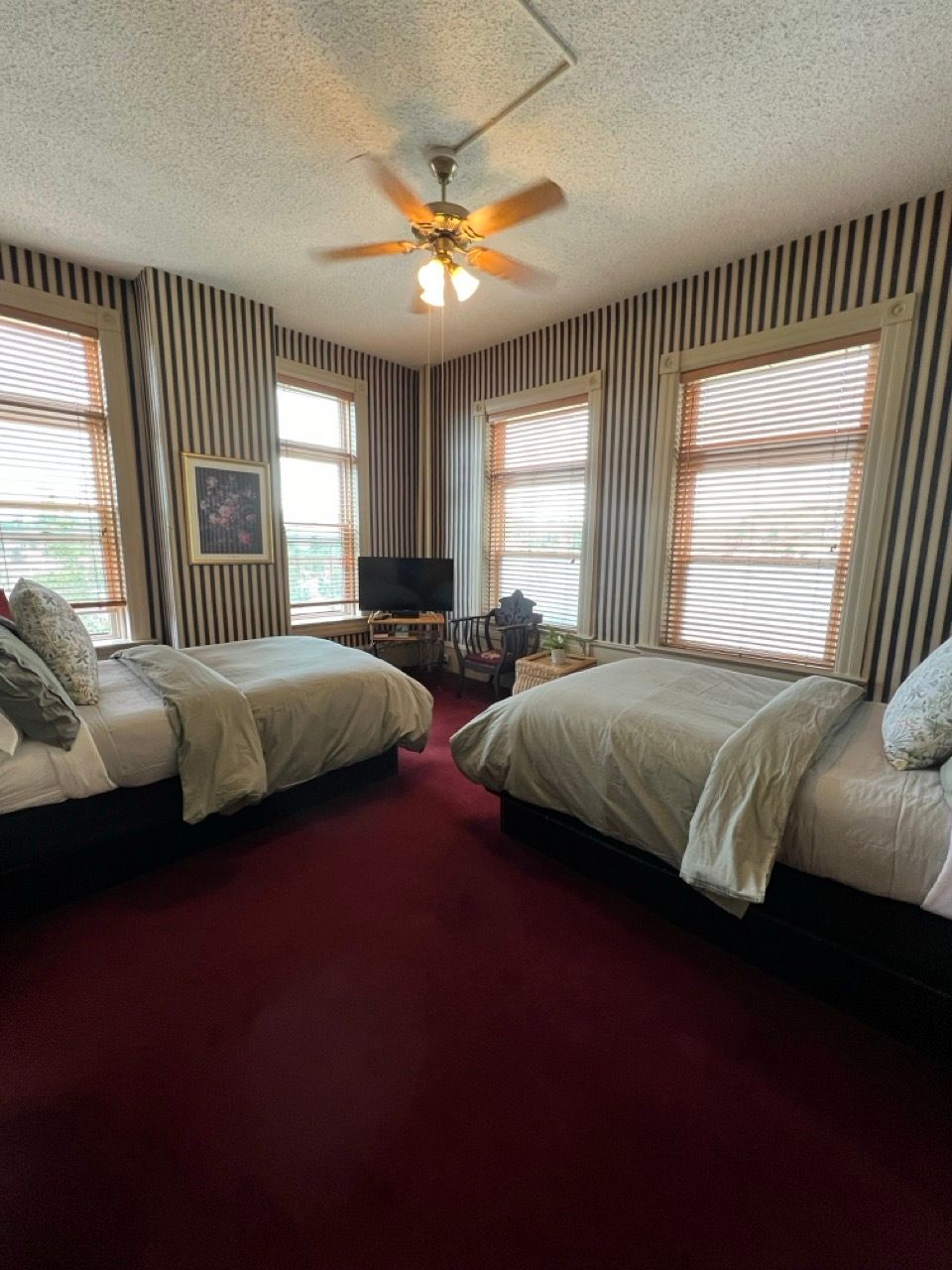 A hotel room with two beds and a ceiling fan.