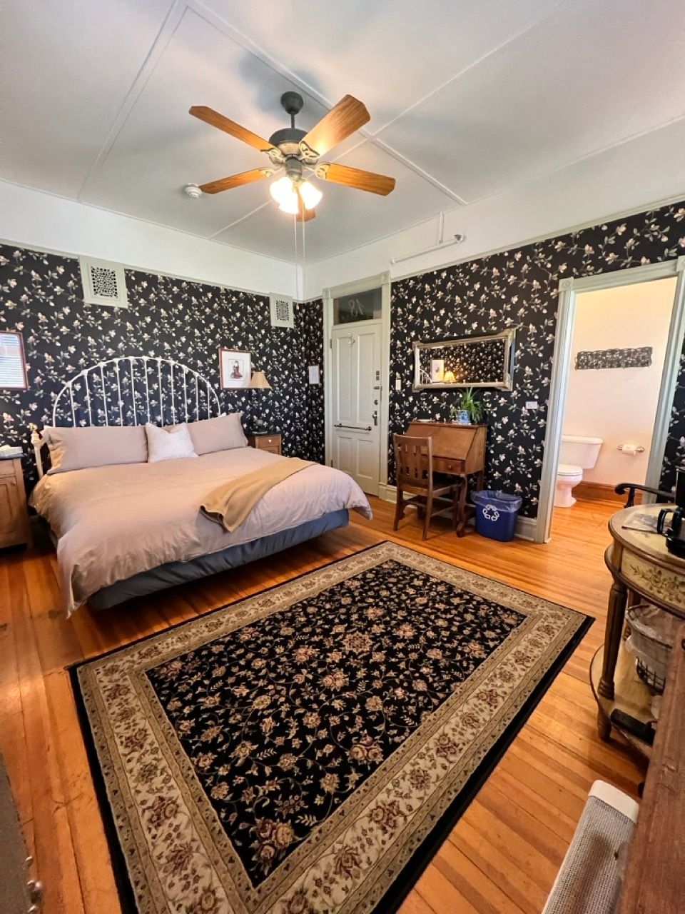 A bedroom with a large bed and a ceiling fan