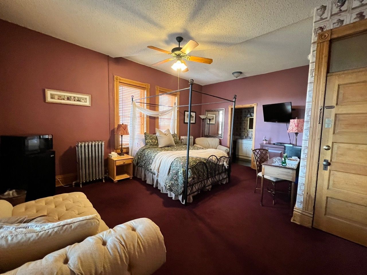 A bedroom with a king size bed , a couch , and a ceiling fan.