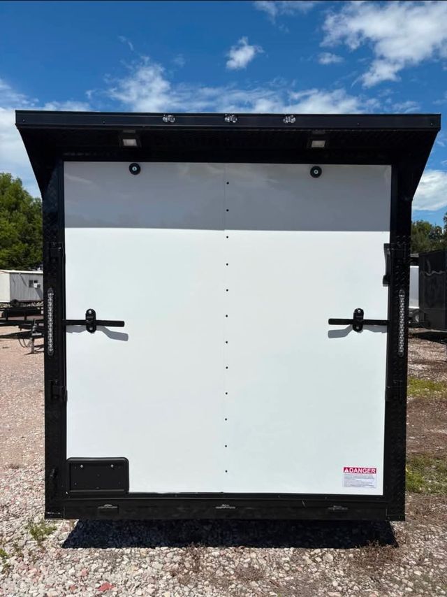 Black and white trailer door with overhead canopy, against a blue sky.