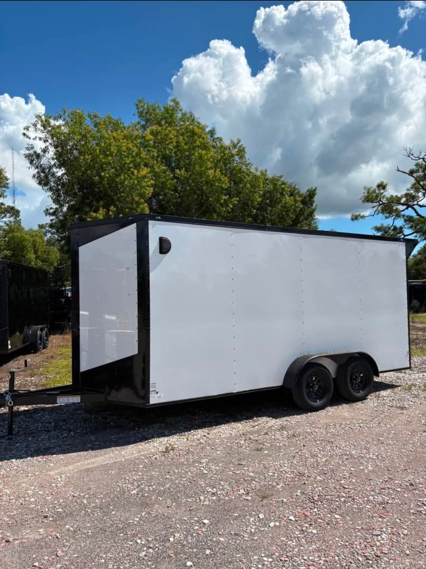 White enclosed cargo trailer with black trim parked outdoors.