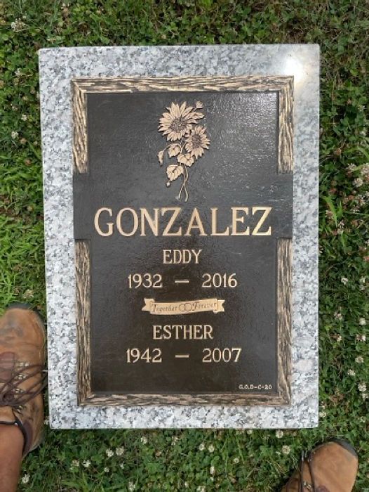 Tombstone with bronze marker. Includes birth and death years and a sunflower design.