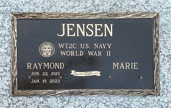 Bronze grave marker on granite base with raised border that has a textured, wood-like appearance.