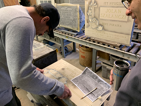 man applying a template on a tomb stone for sandblasting