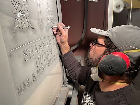 man etching a tombstone by hand