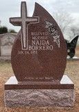 Redish-brown granite tombstone shaped like a teardrop with cross and inscription: