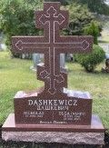 A red granite monument with an Orthodox cross on top in Saints Peter and Paul Russian Orthodox Cemetery, South River, NJ.
