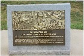 A bronze memorial set on granite honoring all World War veterans. 