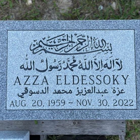 A flat granite footstone with Arabic script.
