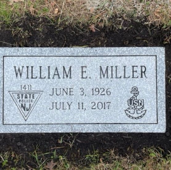 Grey granite footstone with engraved NJ State Police and US Navy emblems.