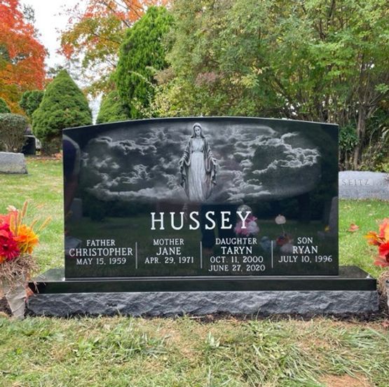A black granite headstone with a laser-etched image of Jesus coming on the clouds.