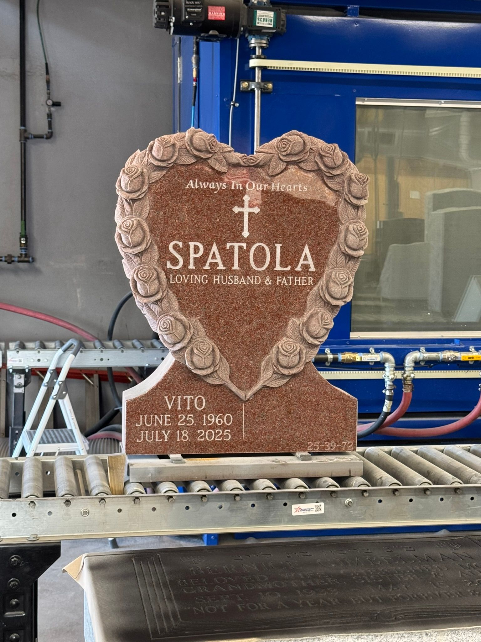 Heart-shaped red granite headstone with floral border;