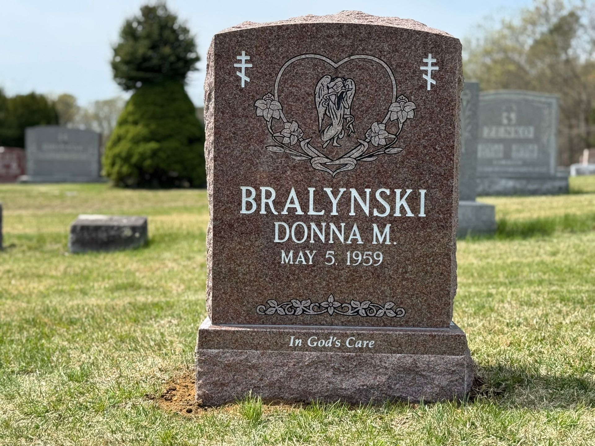 Gravestone of Donna M. Bralynski with heart and cross design, in a cemetery.