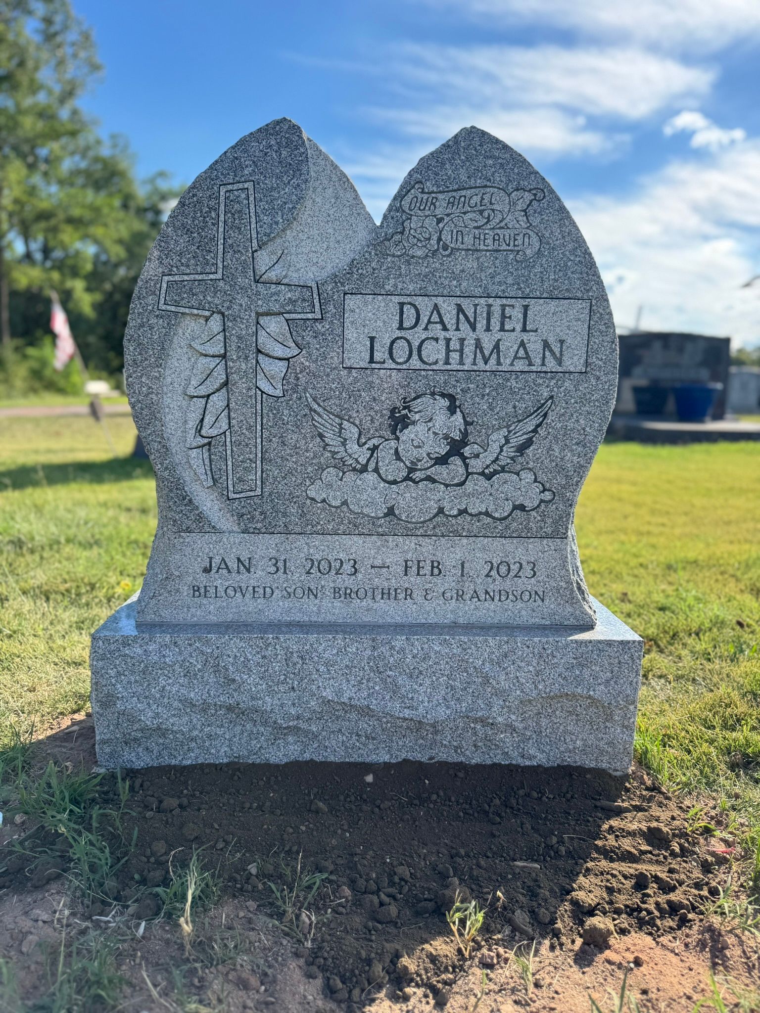 Black granite headstone in teardrop shape with etched image of the deceased.