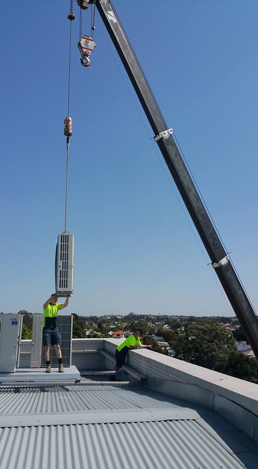 Crane Lifting Inverter Air Conditioner on a  Roof — Air Conditioning in New Lambton, NSW