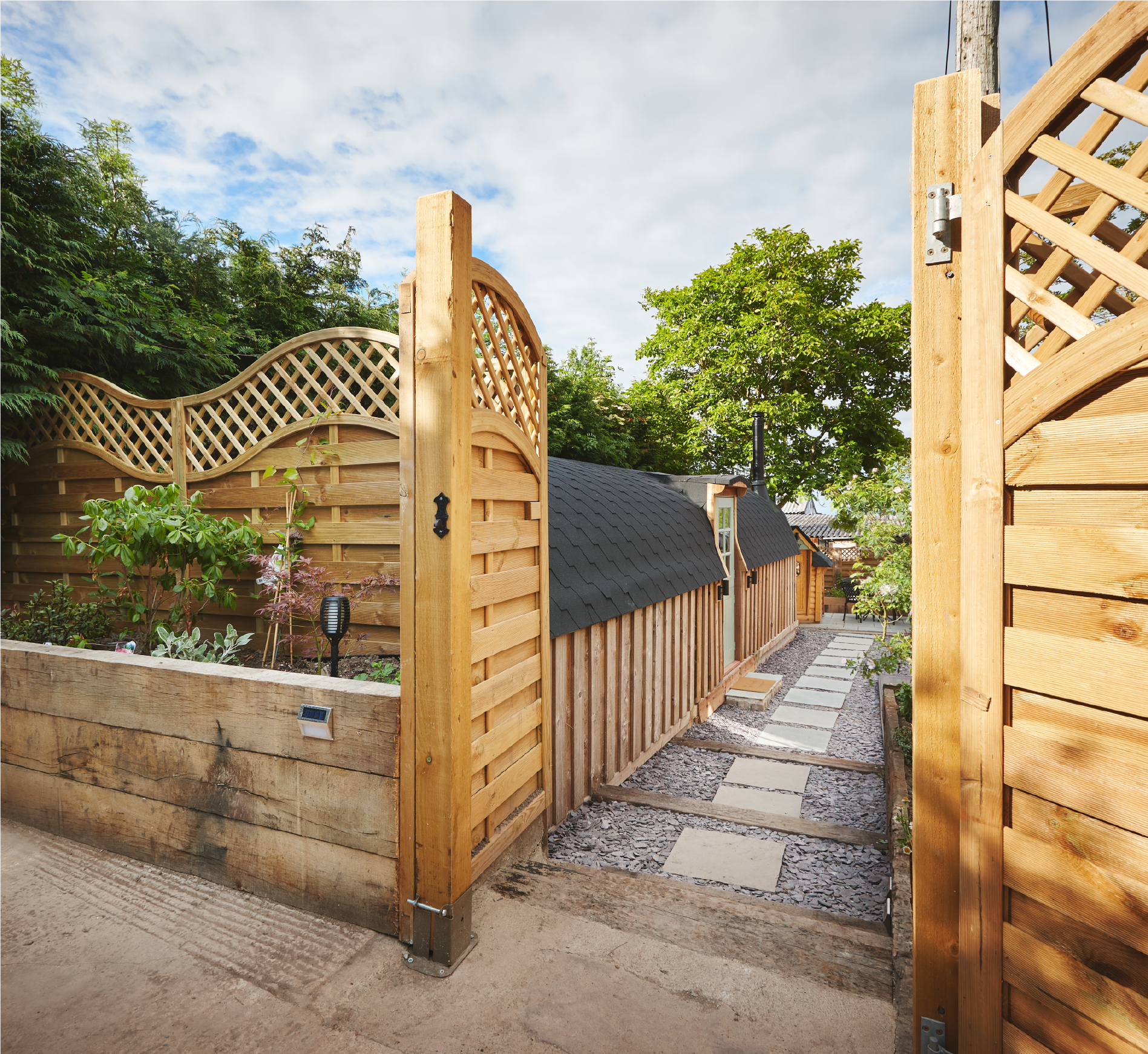 A wooden gate is open to a path leading to a house