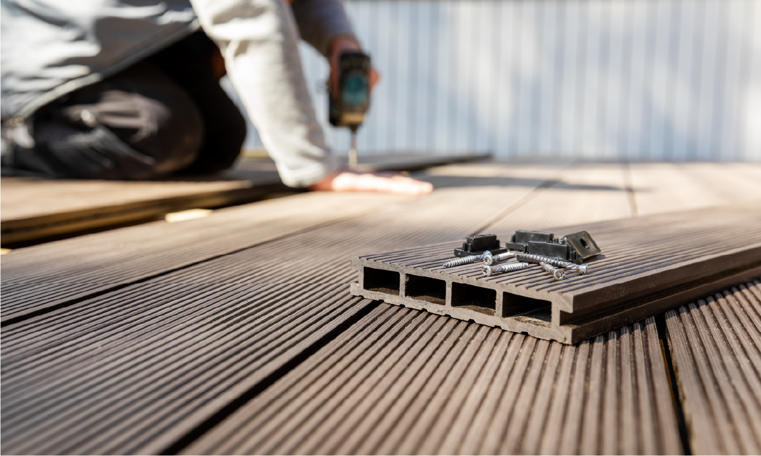 A man is installing a wooden deck with a drill.