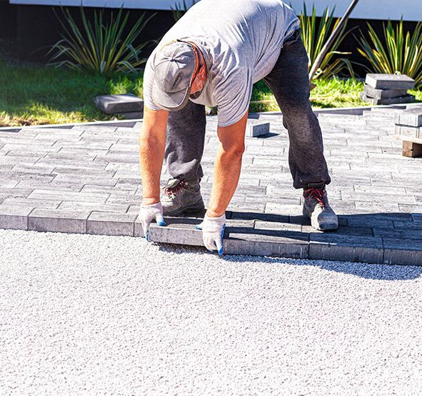 a man is laying bricks on a driveway .