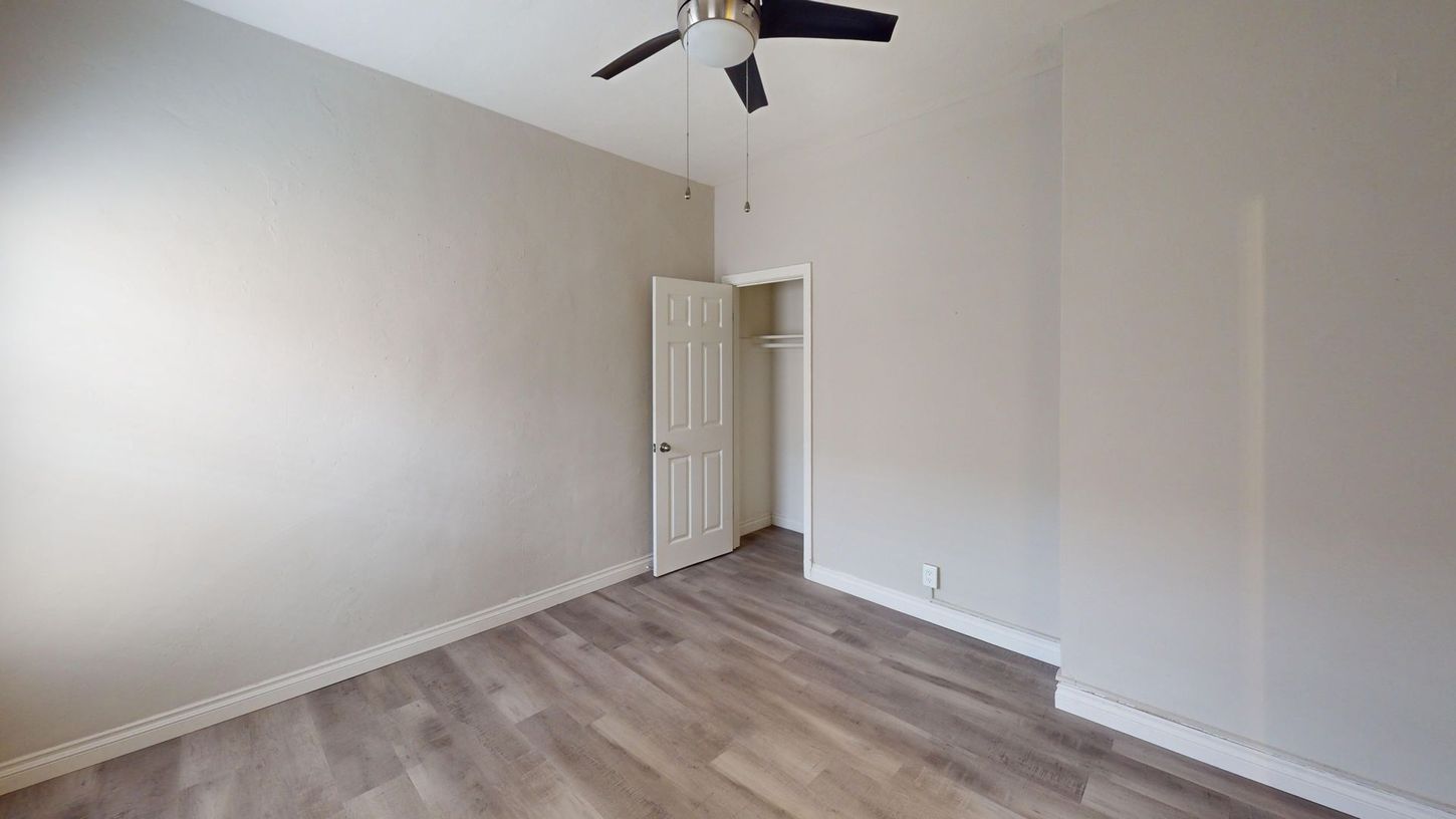 Empty room with gray walls, wood-look flooring, closet, and ceiling fan.