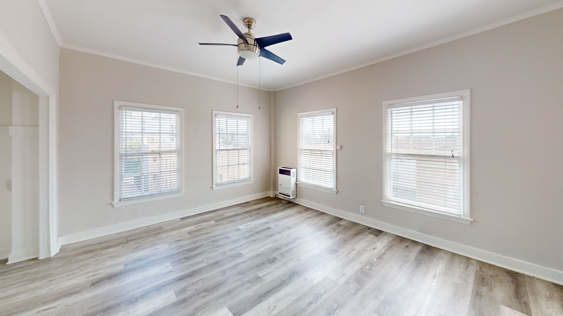 Empty room with three windows, gray flooring, and a blue ceiling fan.