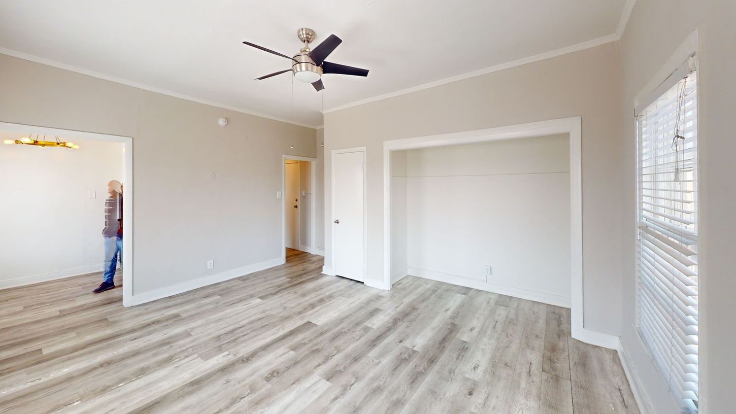 Interior view of a room with hardwood floors, a closet, and a person standing in the doorway.