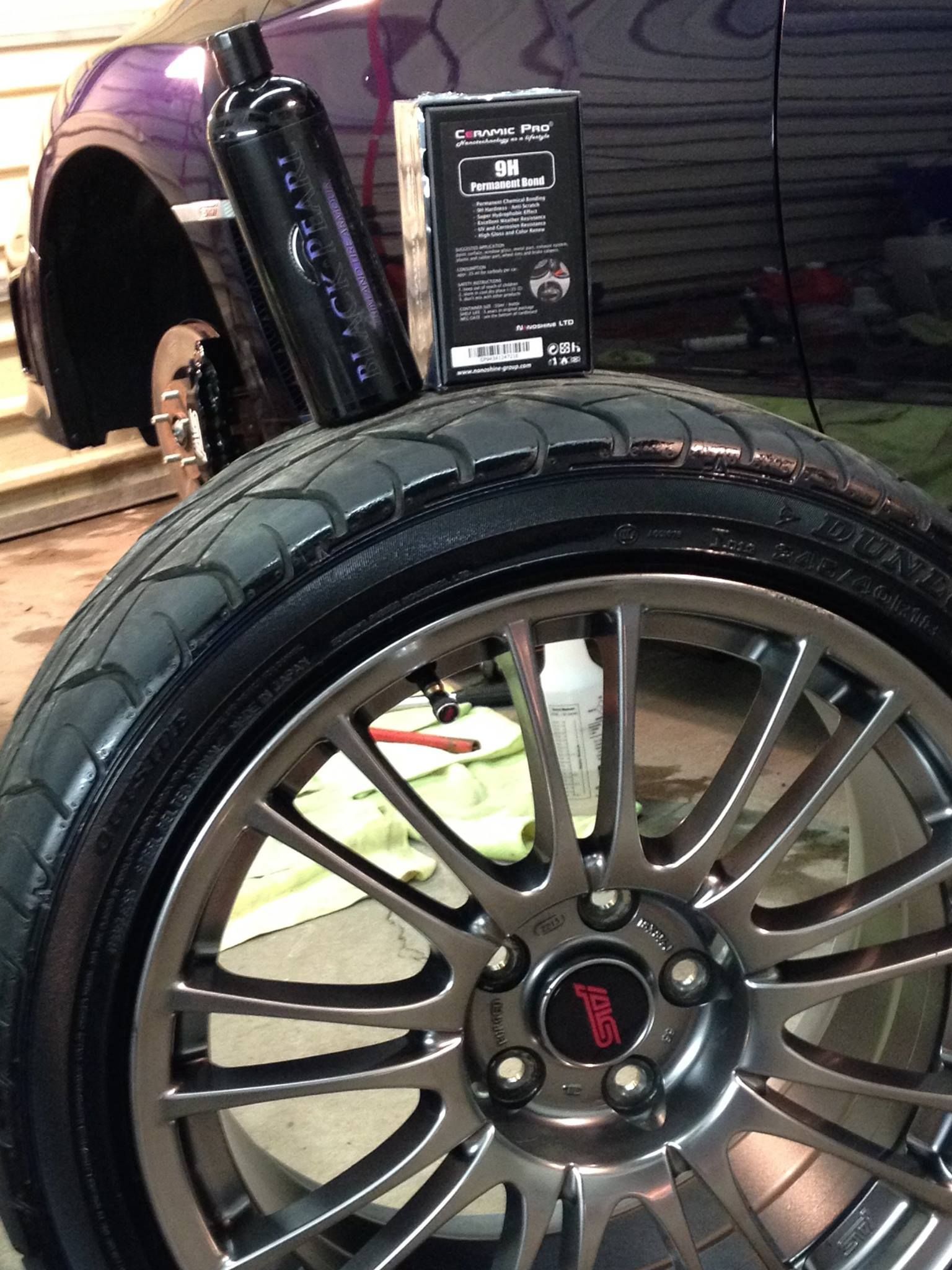 Black Ice Details & Coatings | close up of a tire on a car wheel with a bottle of polish next to it.