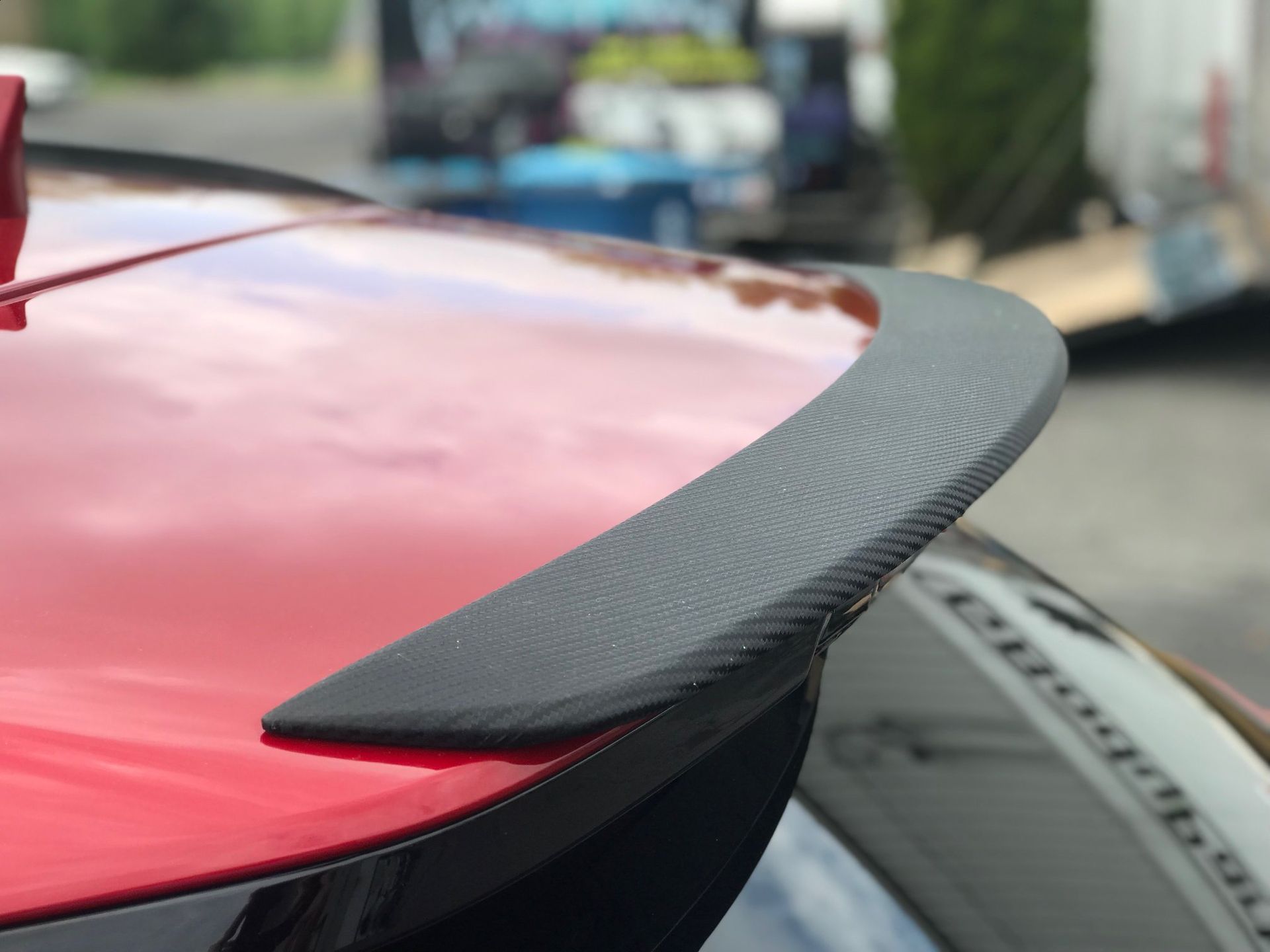 Black Ice Details & Coatings | close up of a red car with a black spoiler on it.