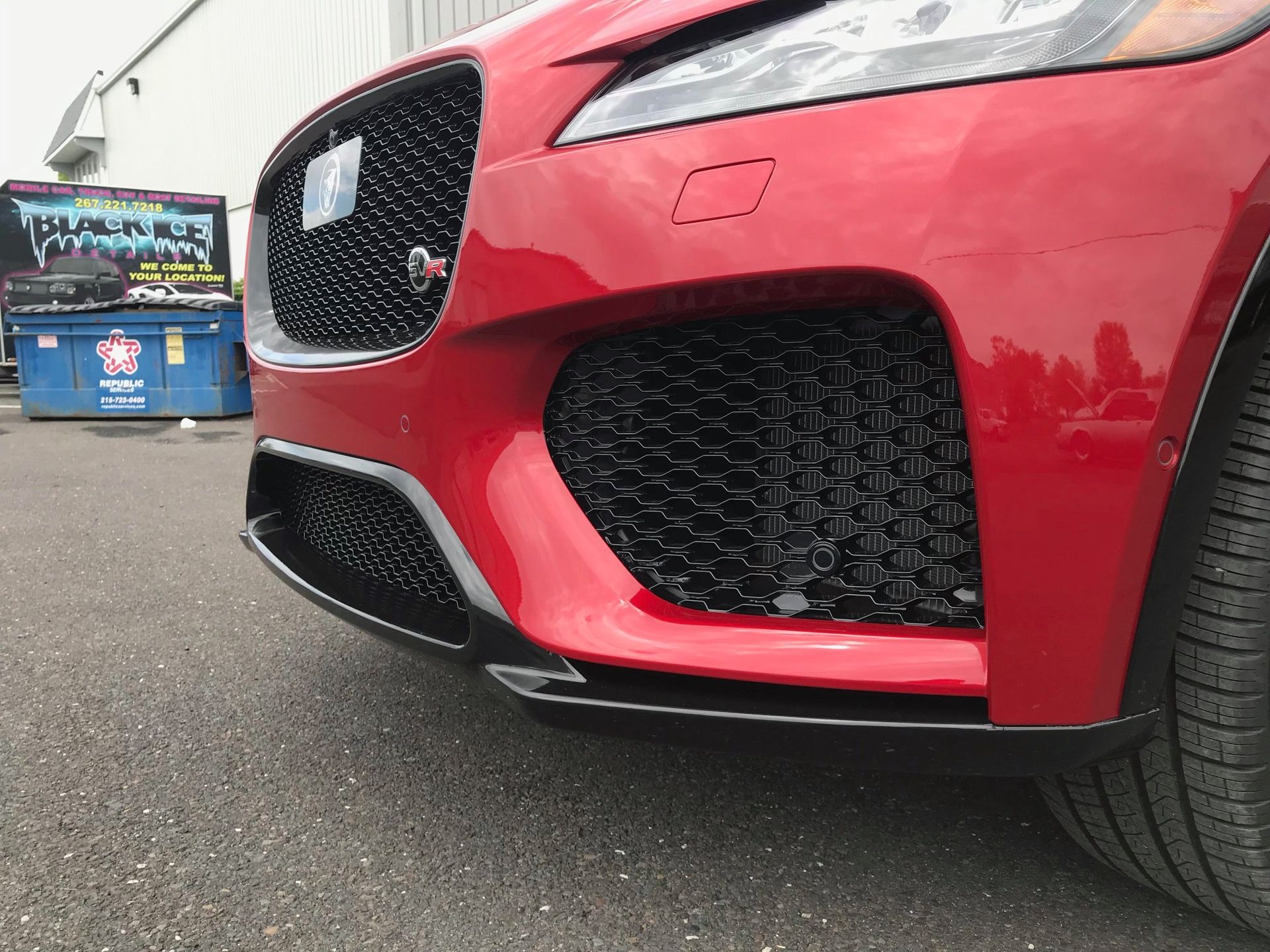 Black Ice Details & Coatings | red car is parked in front of a blue dumpster.