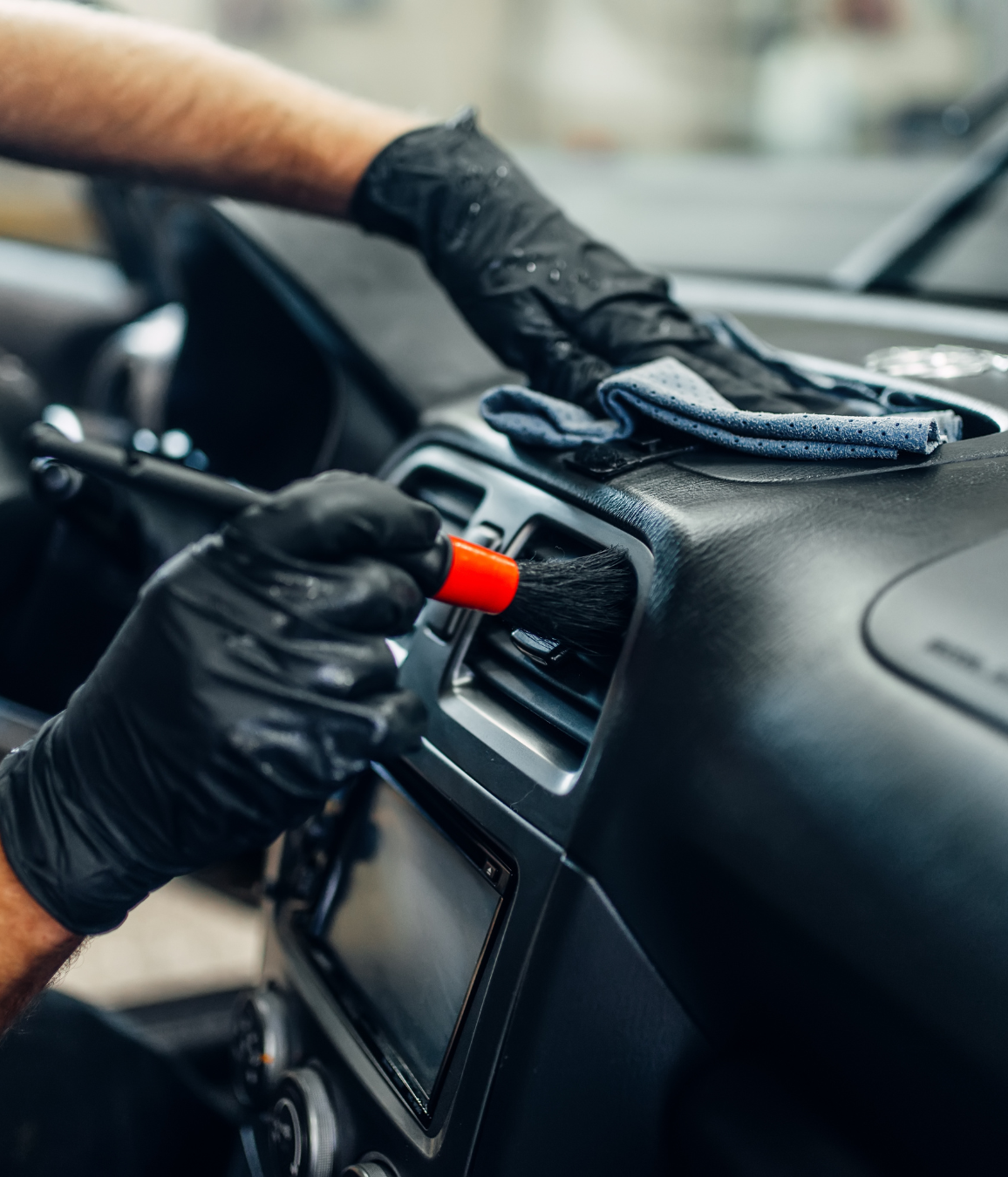 Black Ice Details & Coatings | person wearing black gloves is cleaning the dashboard of a car with a brush.