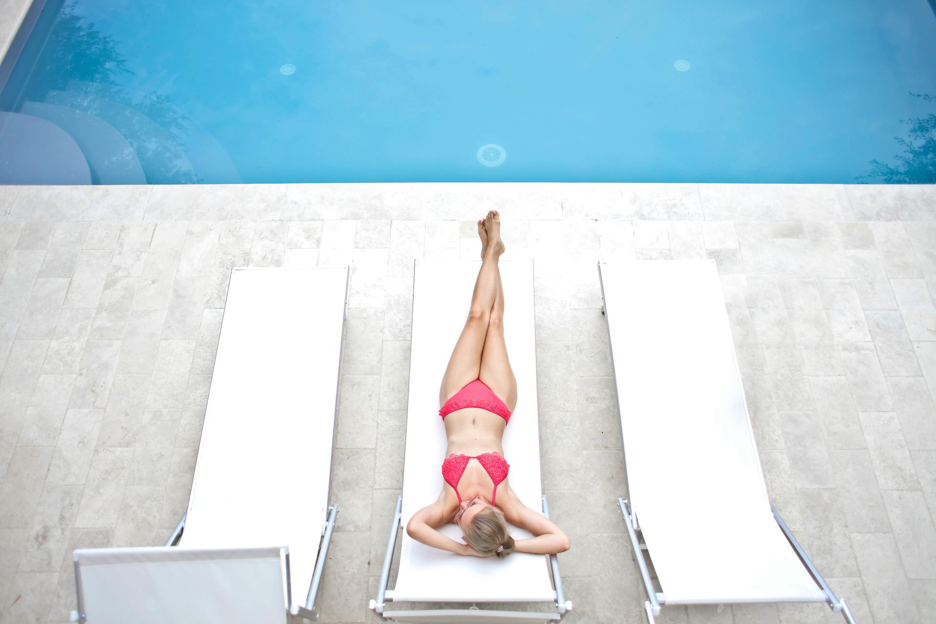 a women lying by a pool on a concrete pool deck